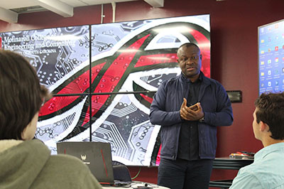 Center for Industry Solutions robotic dog standing in fromt of College of Engineering and Computing wall sign
