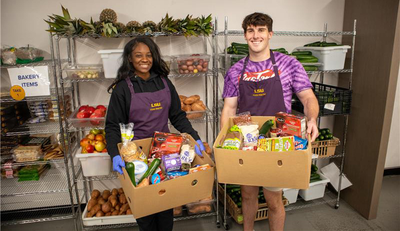 Two students holding full boxes of food at the LSU food pantry